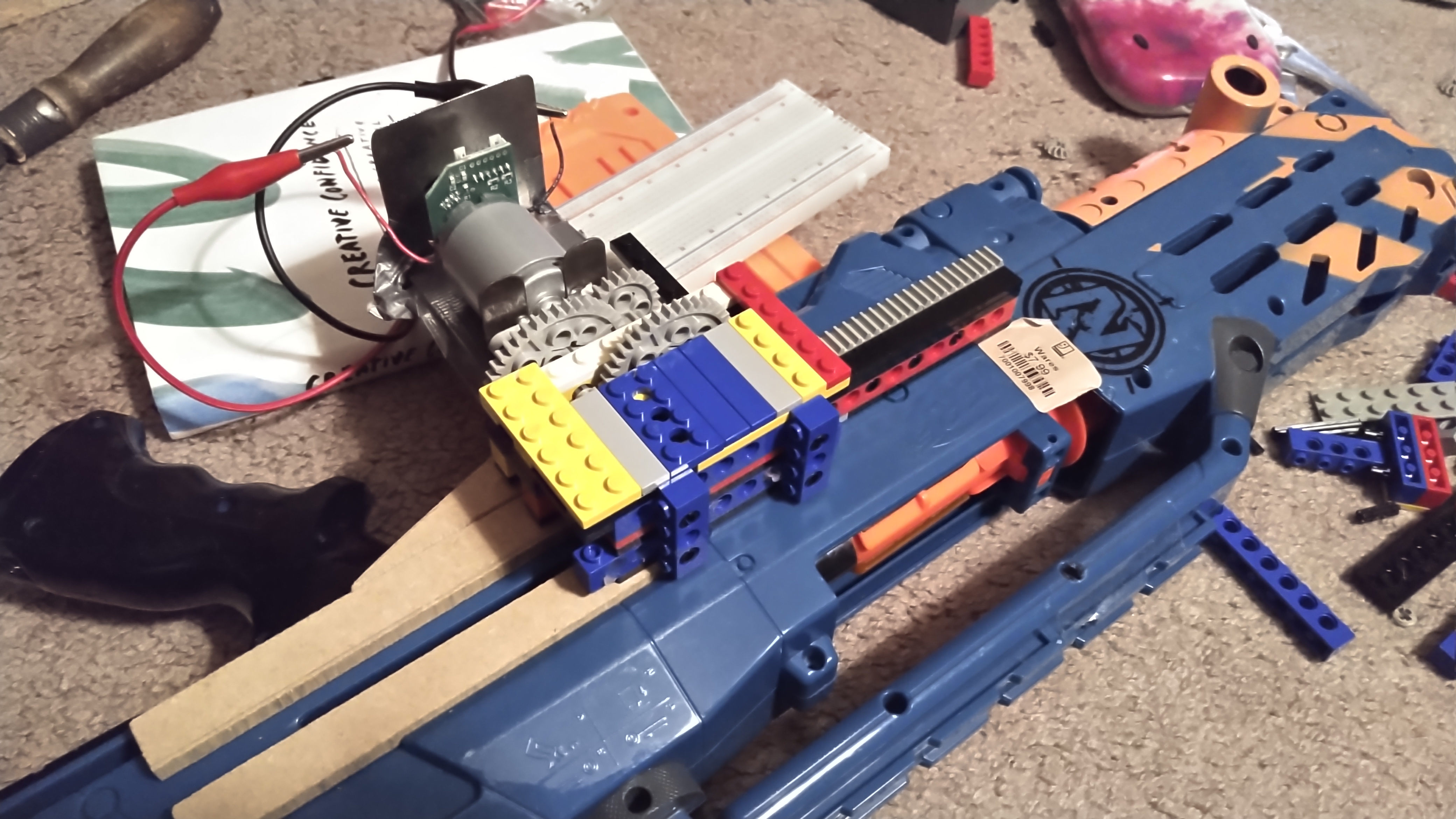 a NERF gun with a motor and LEGO gearbox mounted to its side